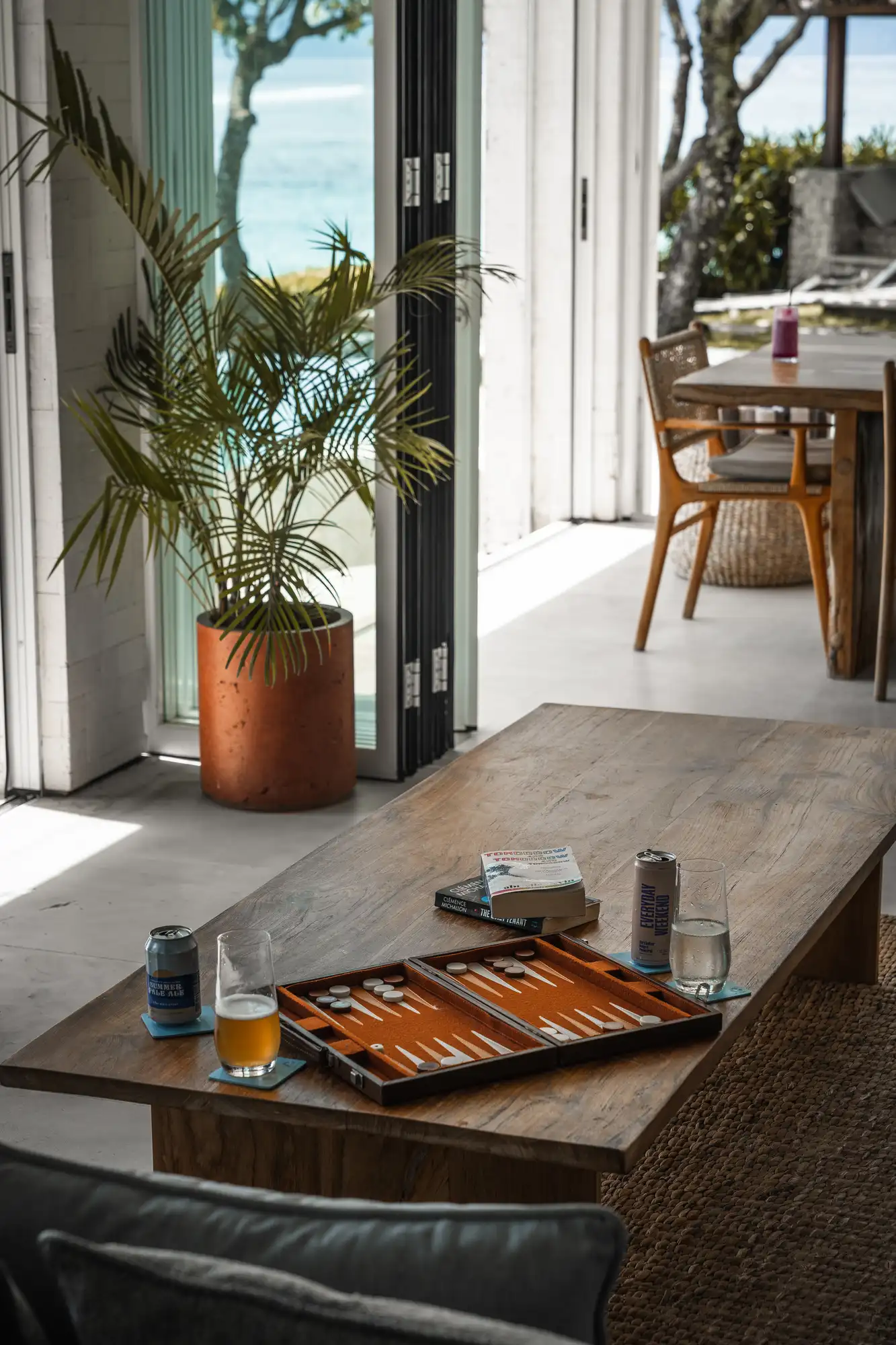 Coffee table with backgammon, beer and books opening onto Song Lambung beach at Lago Beach House