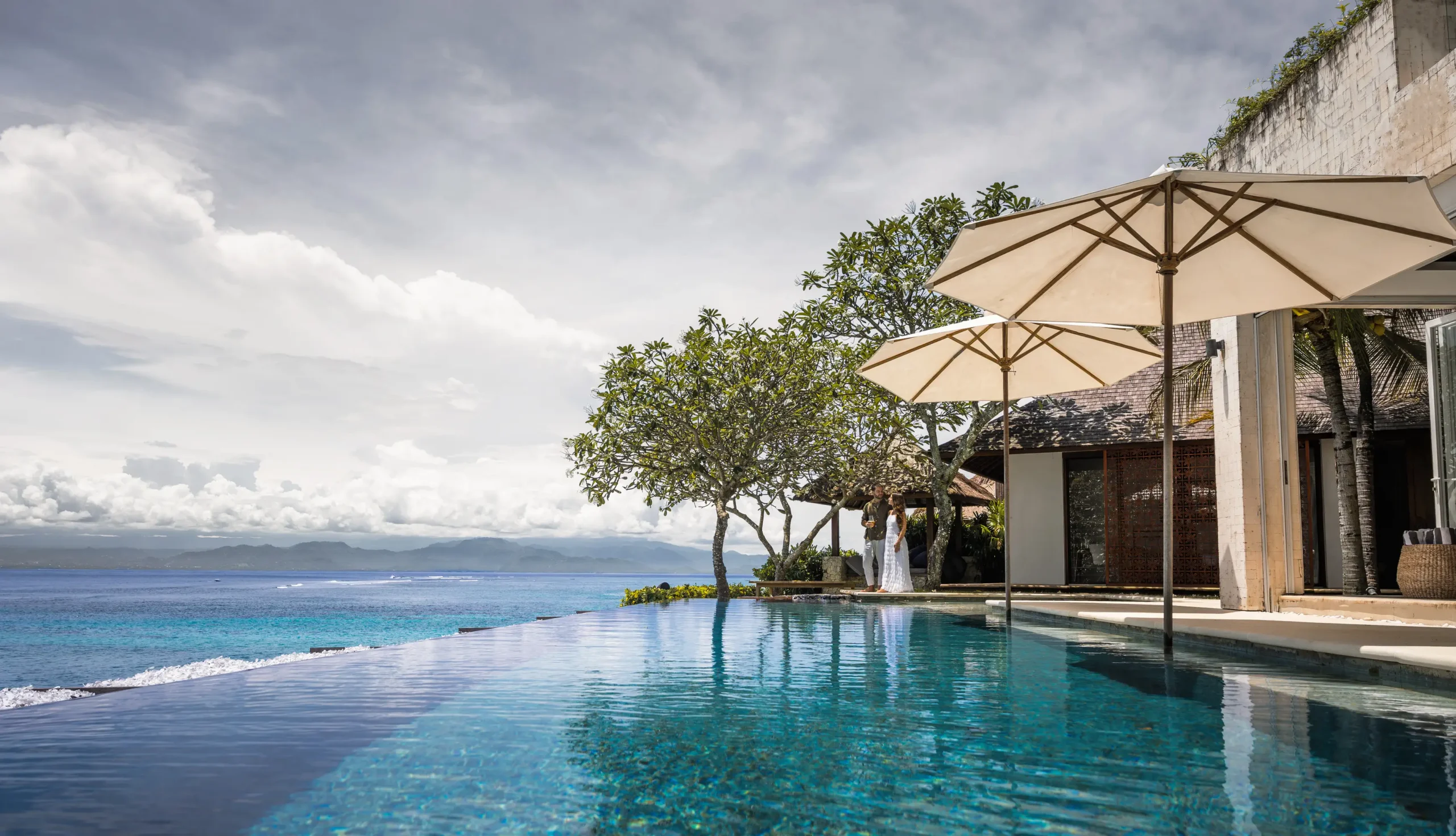 Infinity pool with linen umbrellas and cliff-edge ocean view at Lago Beach House Nusa Lembongan