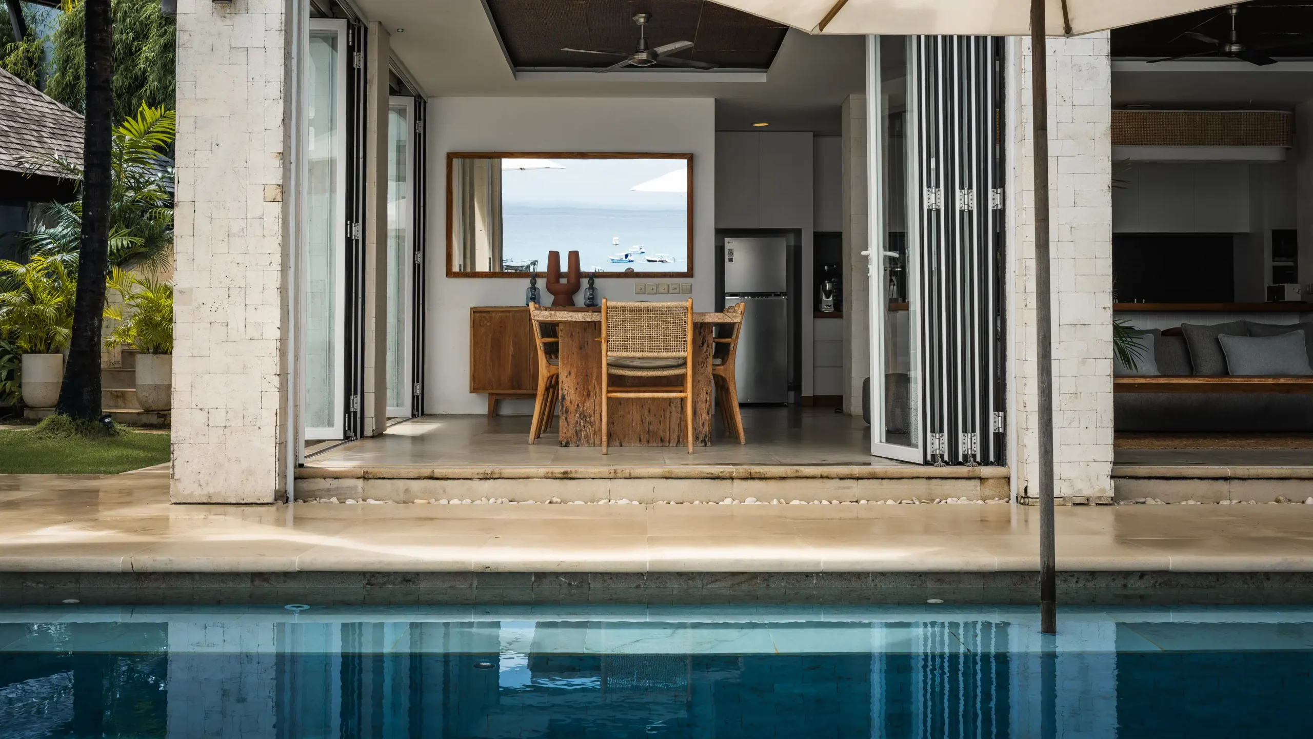 View across the infinity pool to the open dining and kitchen of Lago Beach House Nusa Lembongan
