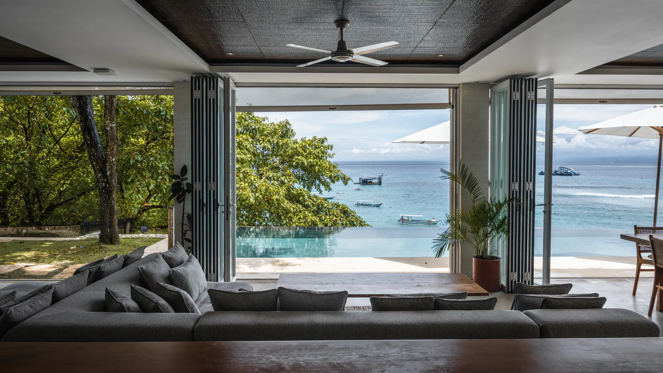 Living room view through bifold doors to the infinity pool, ocean and jukungs at Lago Beach House