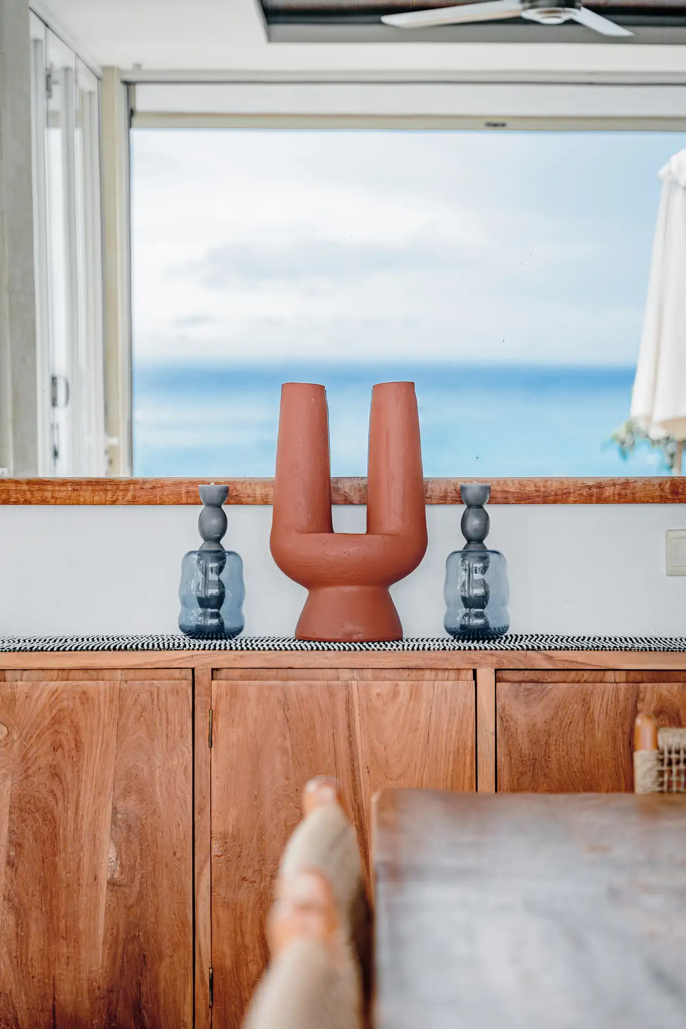 Terracotta vases on a teakwood sideboard with ocean view at Lago Beach House Nusa Lembongan