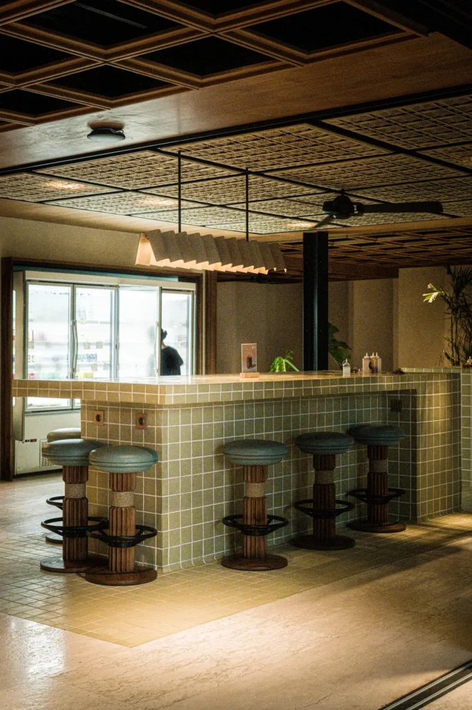 Bar interior with sage tile cladding and leather stools at Dawn cafe Lago Nusa Lembongan