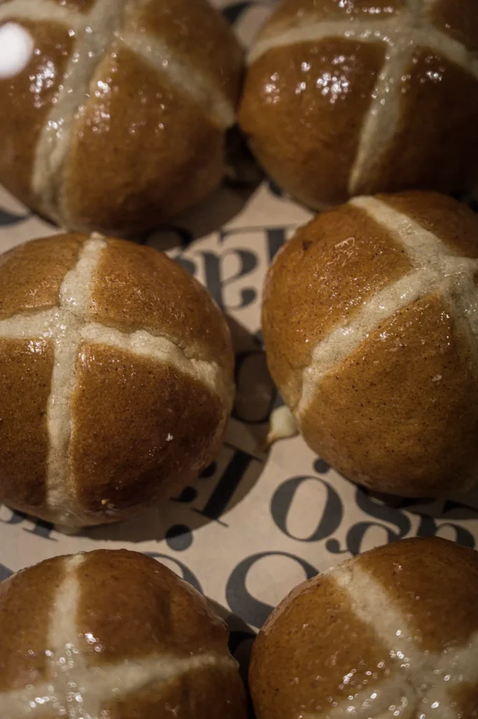 Glazed hot cross buns close-up on Lago-printed paper at Dawn cafe Lago Nusa Lembongan